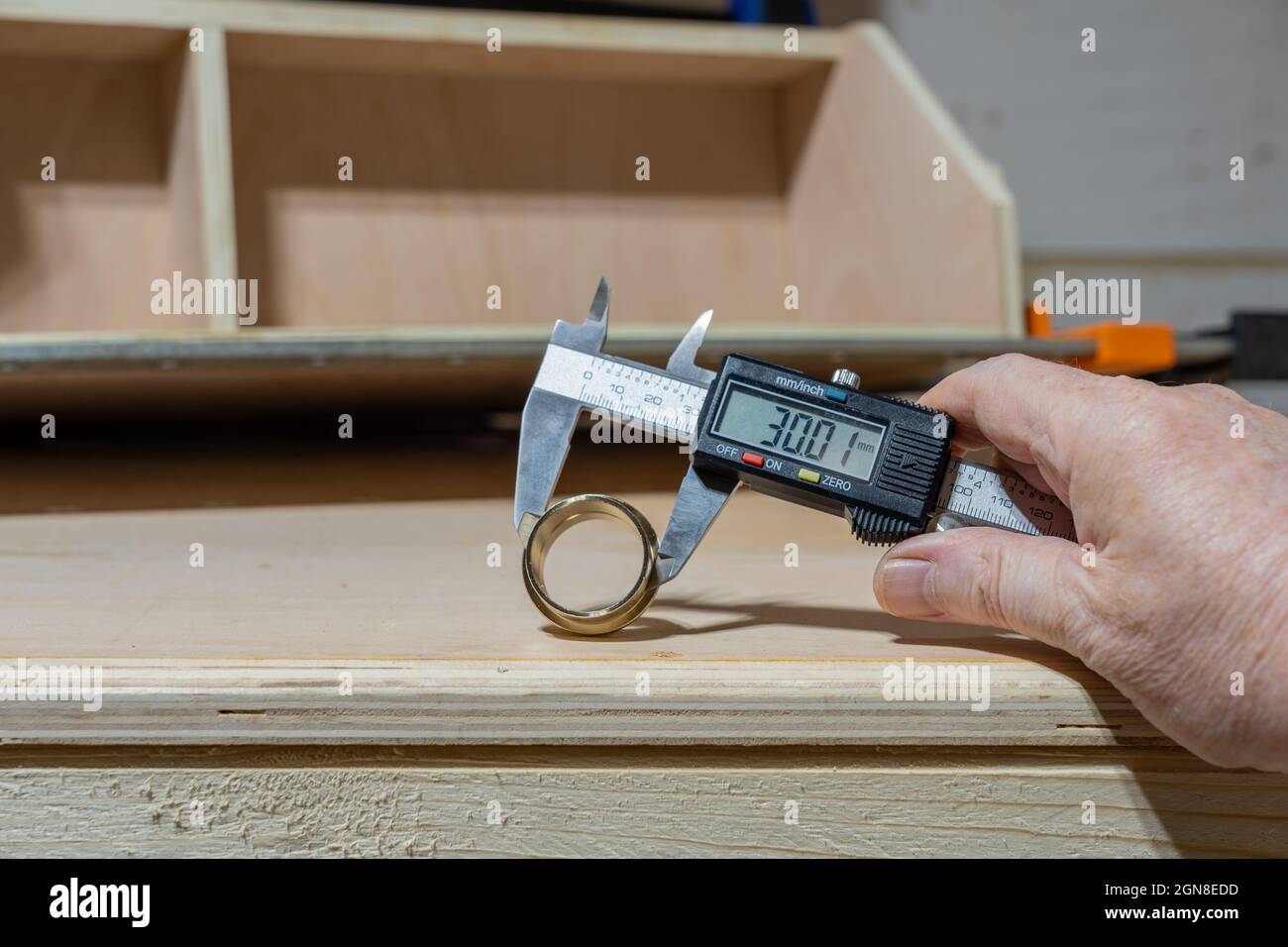 Homme tenant un pied à coulisse numérique mesureur le diamètre externe d'un raccord en laiton Banque D'Images