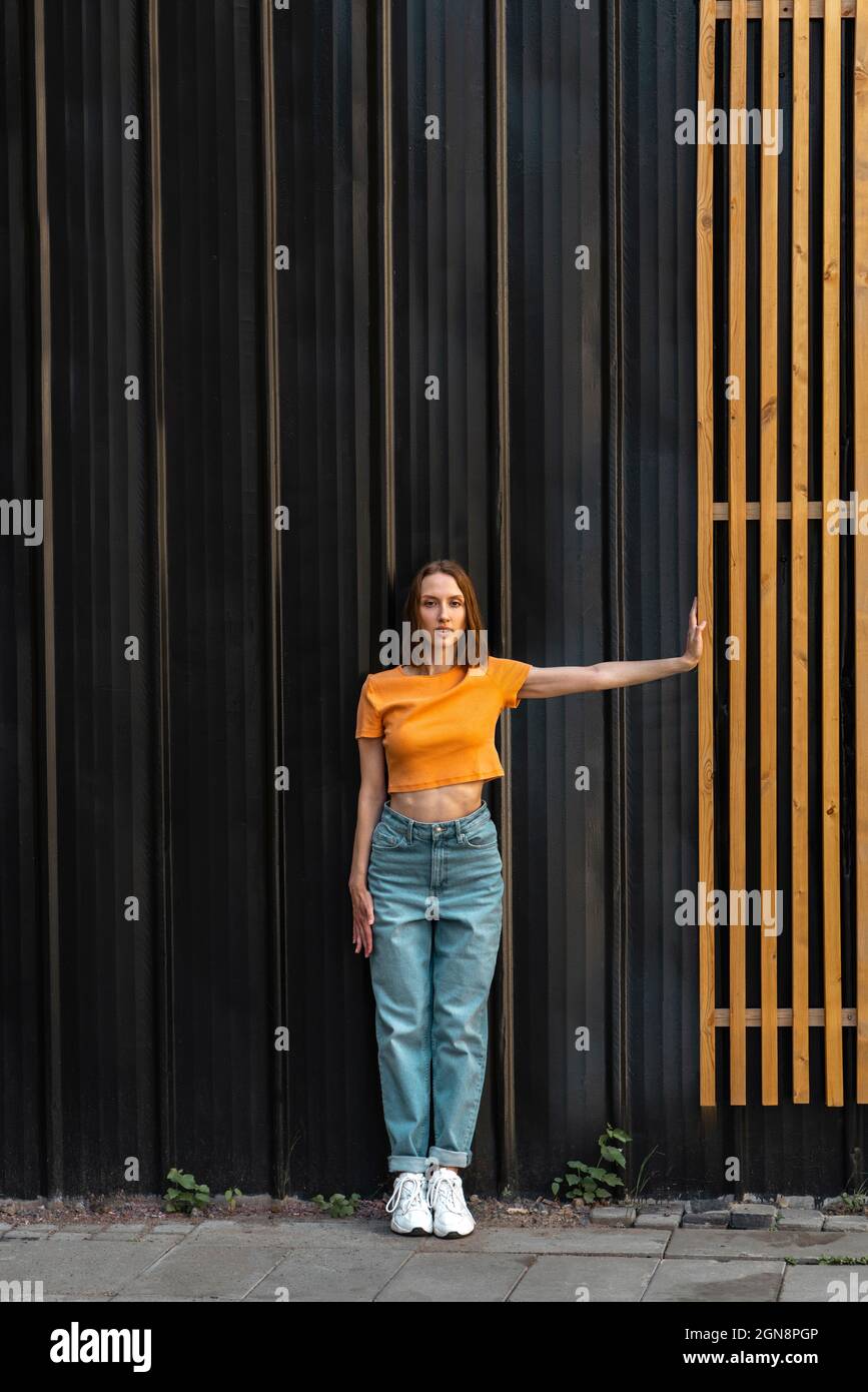 Jeune femme debout devant un mur de couleur noire Banque D'Images