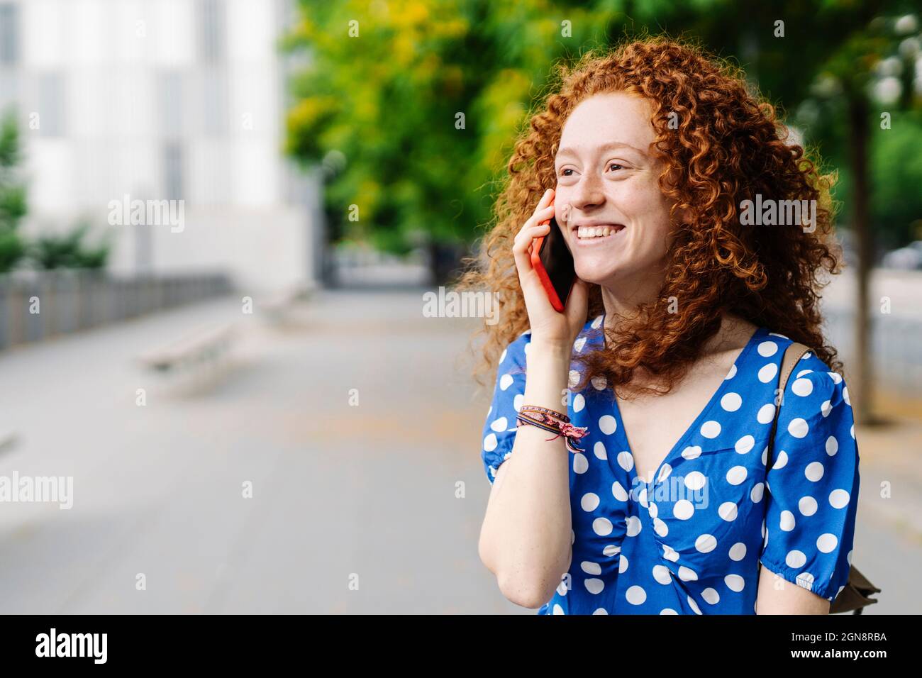 Femme souriante, à tête rouge, parlant sur un téléphone portable Banque D'Images