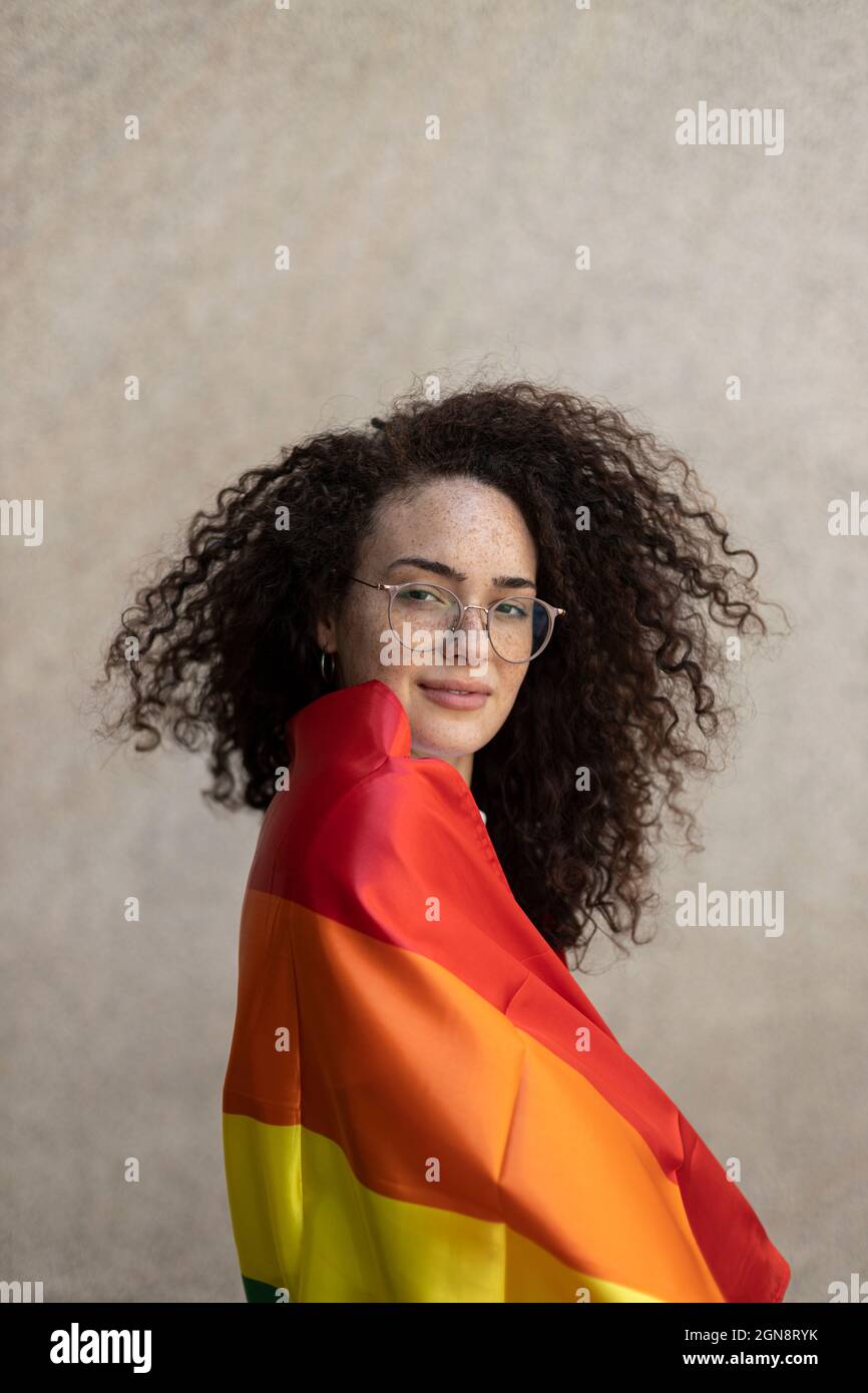 Femme à lunettes enveloppée dans un drapeau arc-en-ciel Banque D'Images