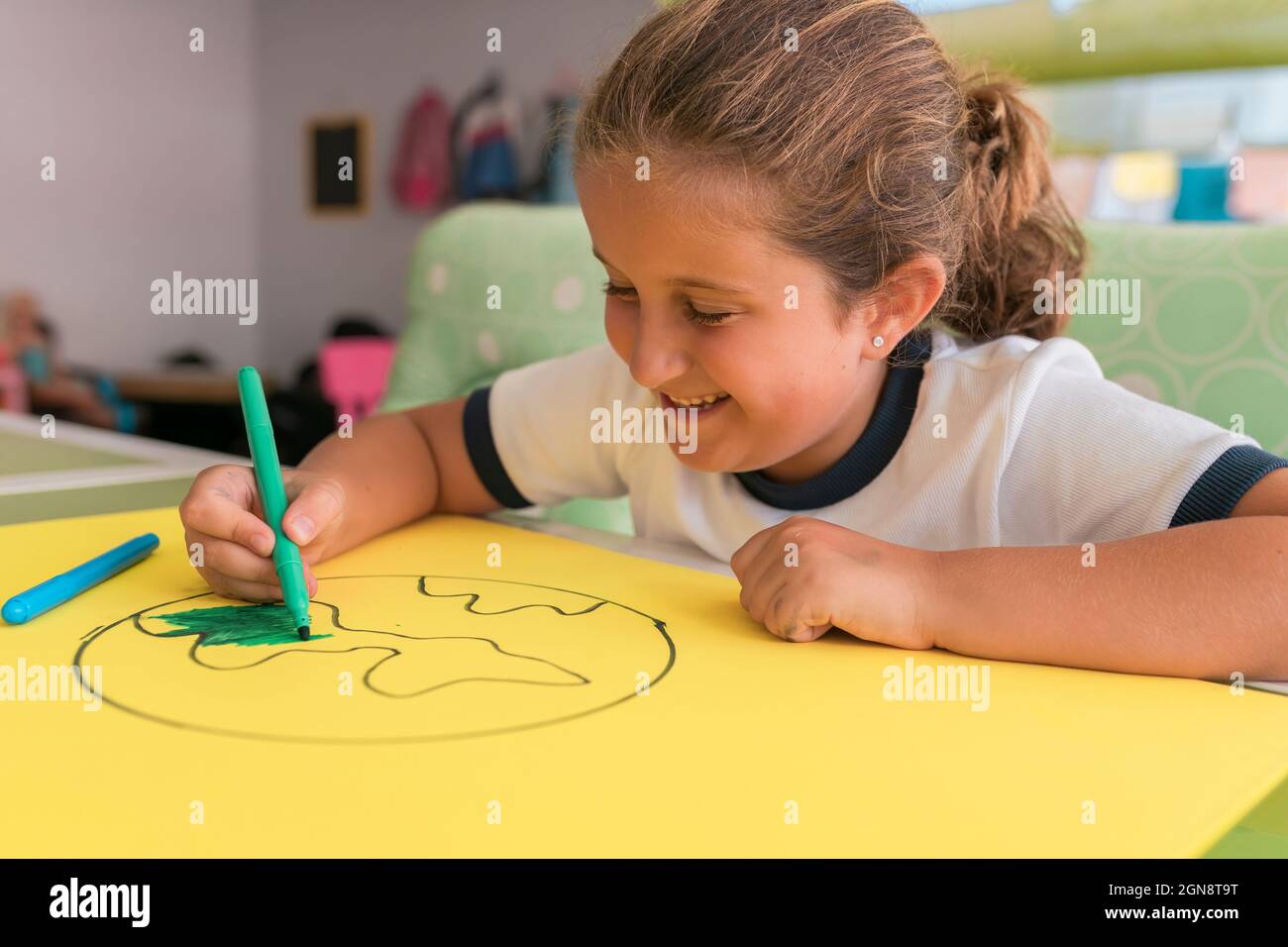 Jolie fille souriante colorant dessin terre à la maison Banque D'Images