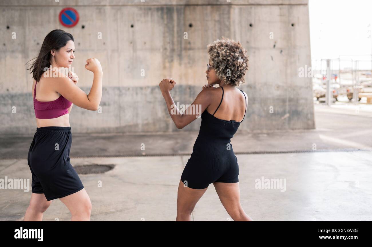 Les femmes adultes de taille moyenne qui poinçonnage tout en pratiquant la boxe ensemble Banque D'Images