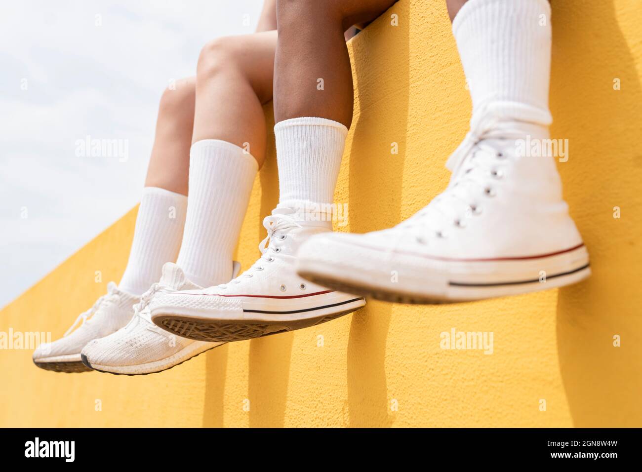 Les femmes de taille moyenne portent des chaussures de sport blanches sur  un mur de soutènement jaune Photo Stock - Alamy