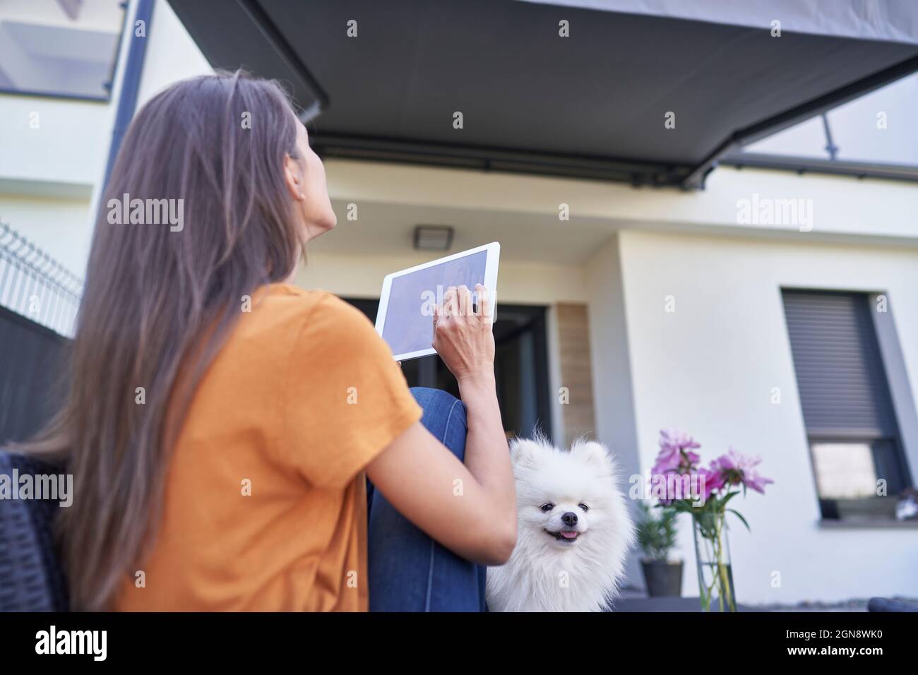 Femme ouvrant la maison à l'extérieur grâce à une tablette numérique Banque D'Images