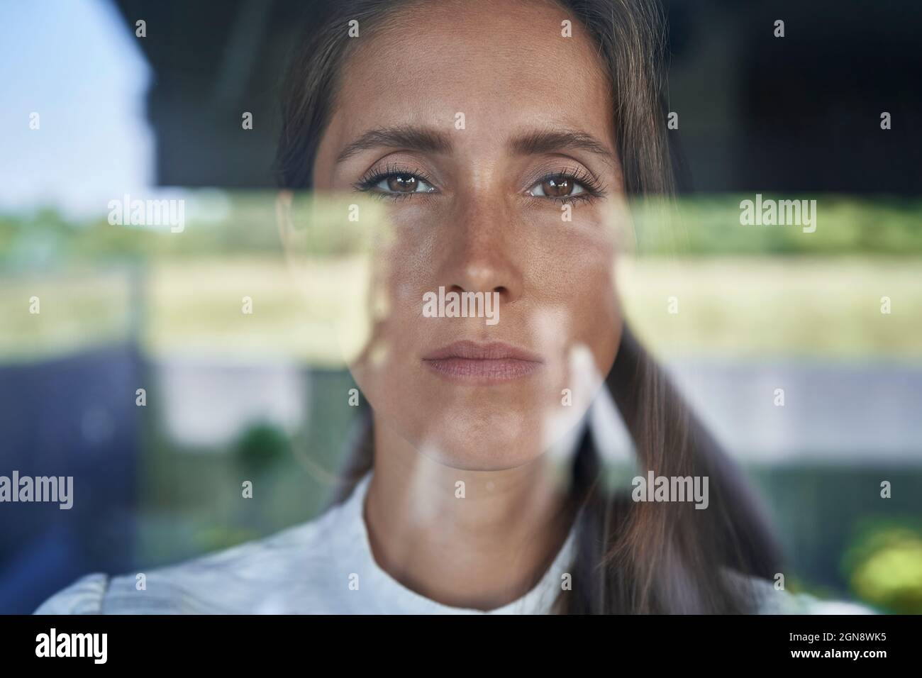 Femme sérieuse regardant à travers le verre Banque D'Images