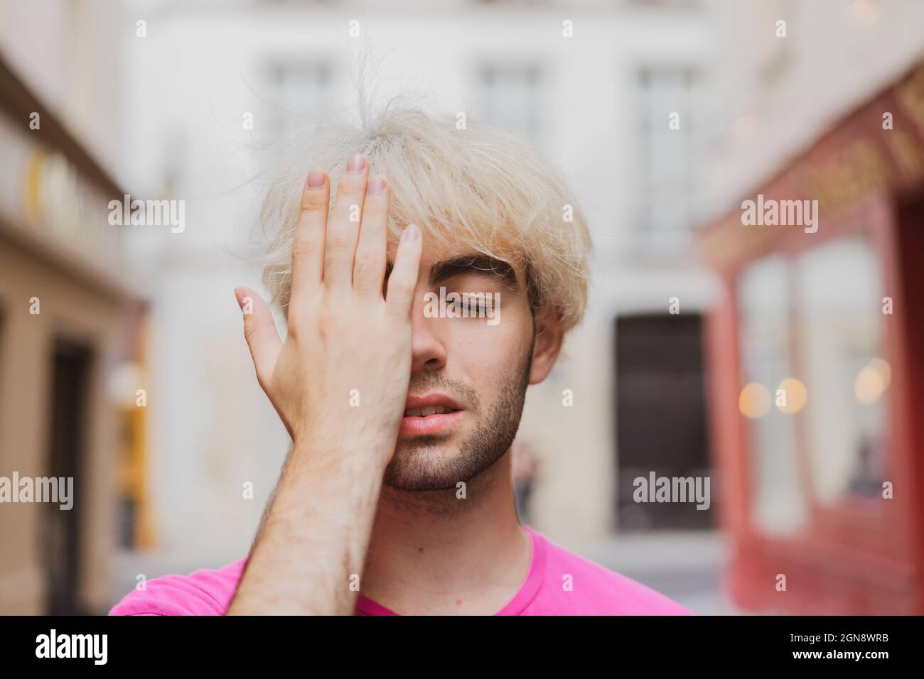 Jeune homme gay avec les yeux fermés couvrant le visage avec la main Banque D'Images