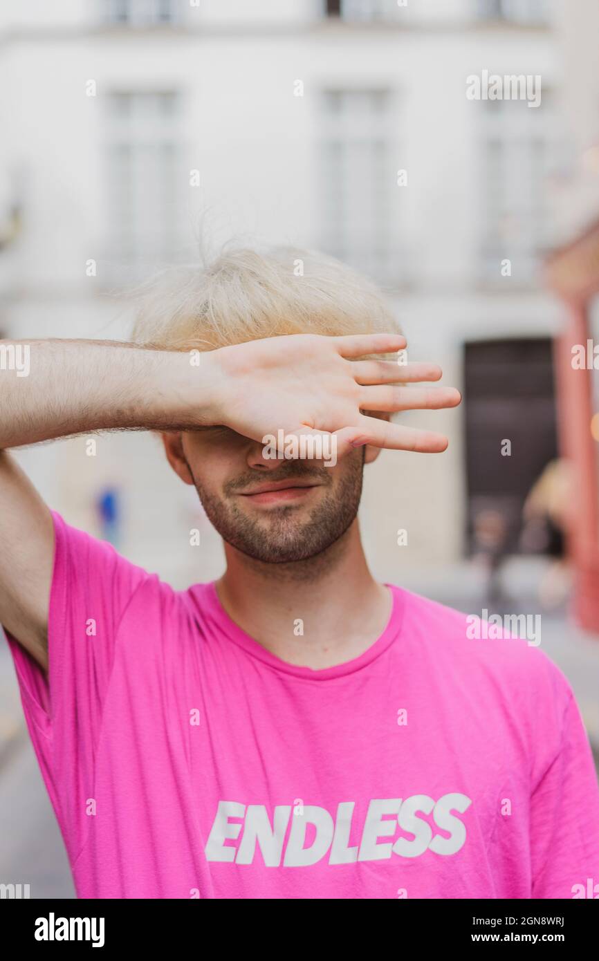 Jeune homme gay souriant couvrant les yeux avec la main Banque D'Images
