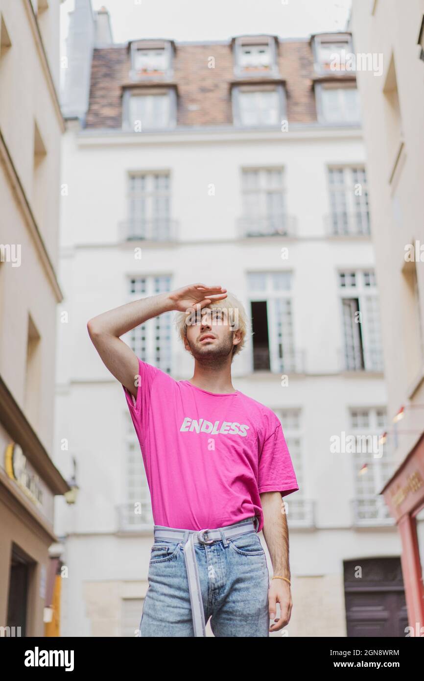 Jeune homme gay portant un T-shirt rose qui protège les yeux dans la ville Banque D'Images