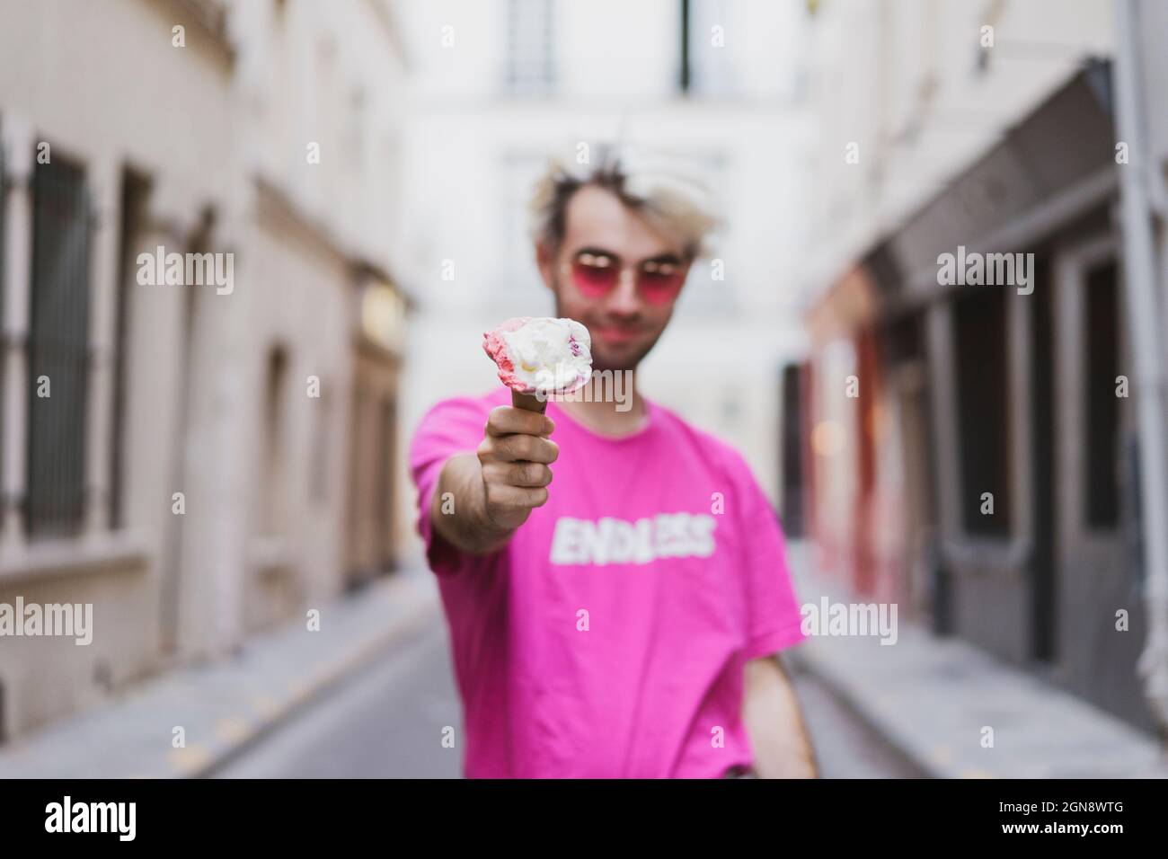 Jeune homme gay portant un t-shirt rose offrant de la crème glacée Banque D'Images