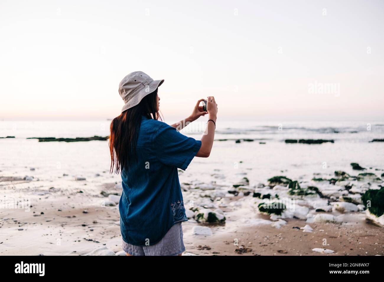 Femme portant un chapeau photographiant à la plage pendant les vacances Banque D'Images