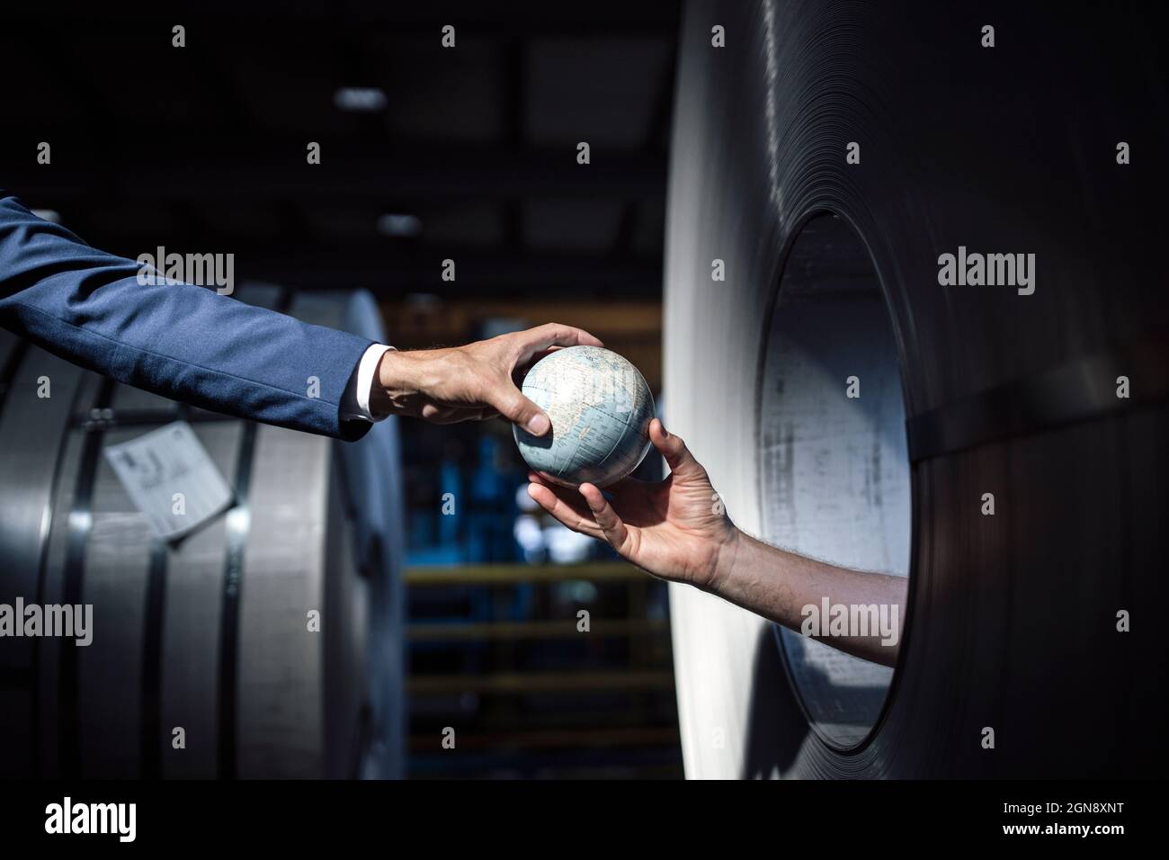 Homme d'affaires recevant un globe de la main à l'intérieur d'un rouleau en acier Banque D'Images