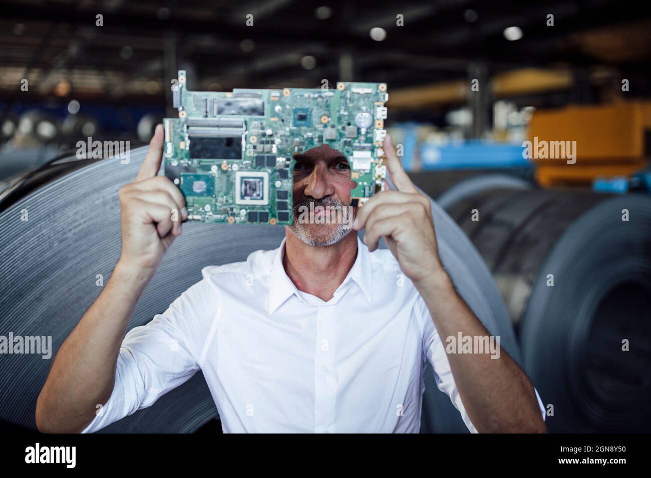 Homme professionnel regardant à travers la carte de circuit imprimé dans l'industrie de l'acier Banque D'Images