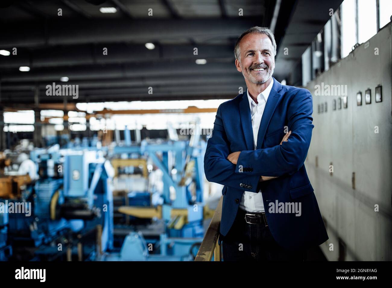 Un homme d'affaires souriant aux bras croisés sur l'industrie de l'acier Banque D'Images