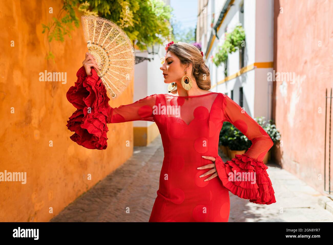Danseuse avec un ventilateur traditionnel et une robe debout dans une allée Banque D'Images