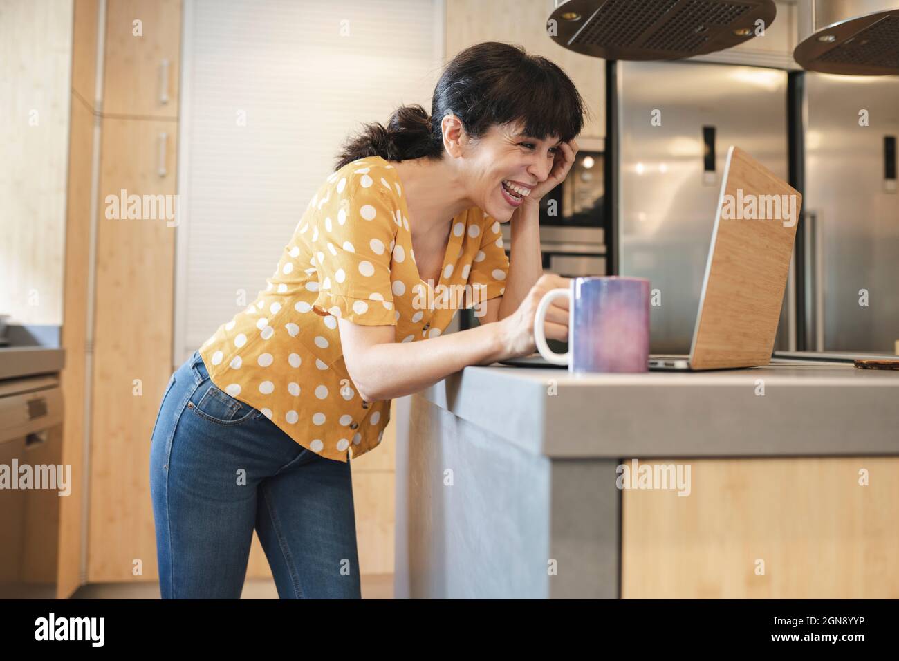 Une femme mûre riant pendant les appels vidéo par ordinateur portable pendant les rencontres en ligne Banque D'Images