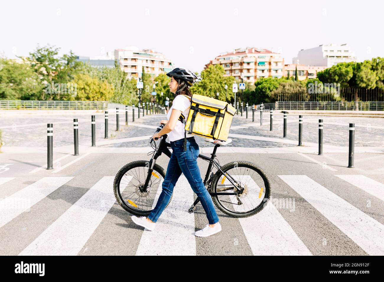 Femme de livraison avec sac à dos vélo de roue sur la route pendant la journée ensoleillée Banque D'Images