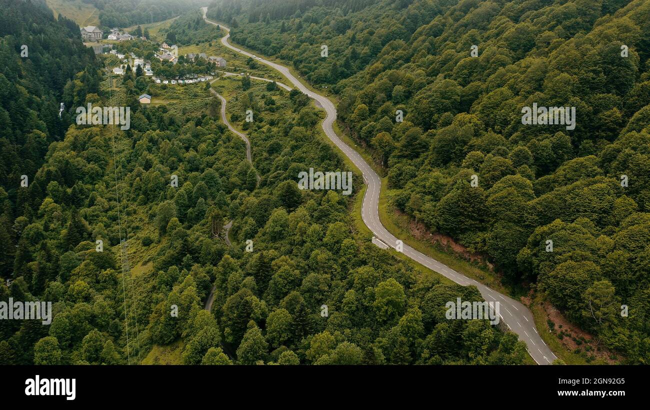 Panorama aérien de la route de campagne serpentant à travers la vallée verdoyante boisée Banque D'Images
