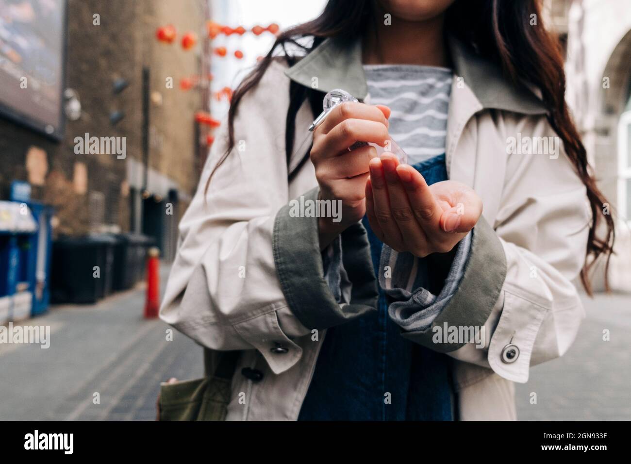 Femme utilisant un désinfectant pour les mains dans la rue Banque D'Images