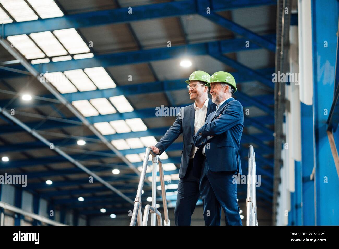Directeurs généraux masculins avec hardhat debout en usine Banque D'Images