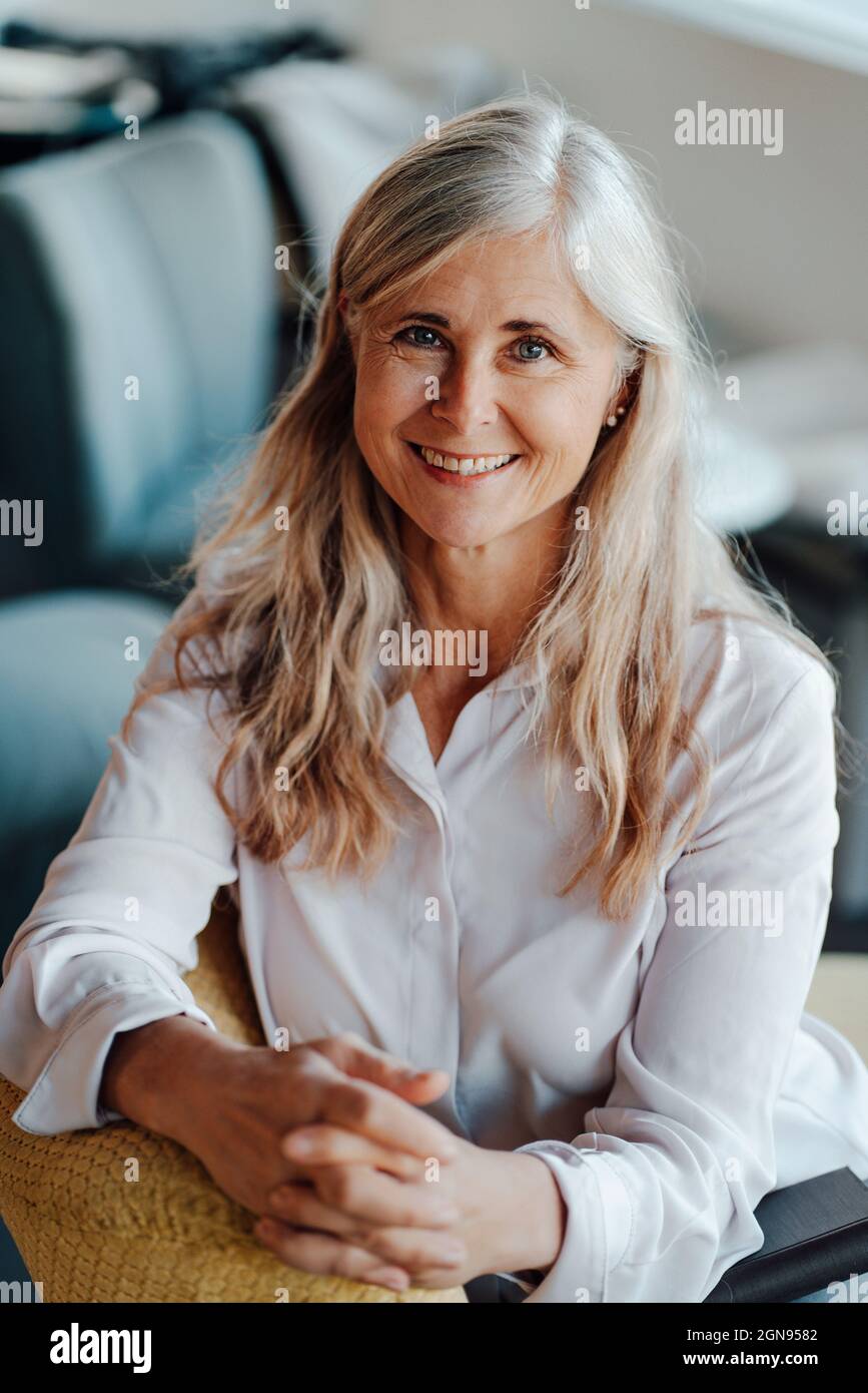 Femme mûre souriante avec de longs cheveux gris dans le café Banque D'Images