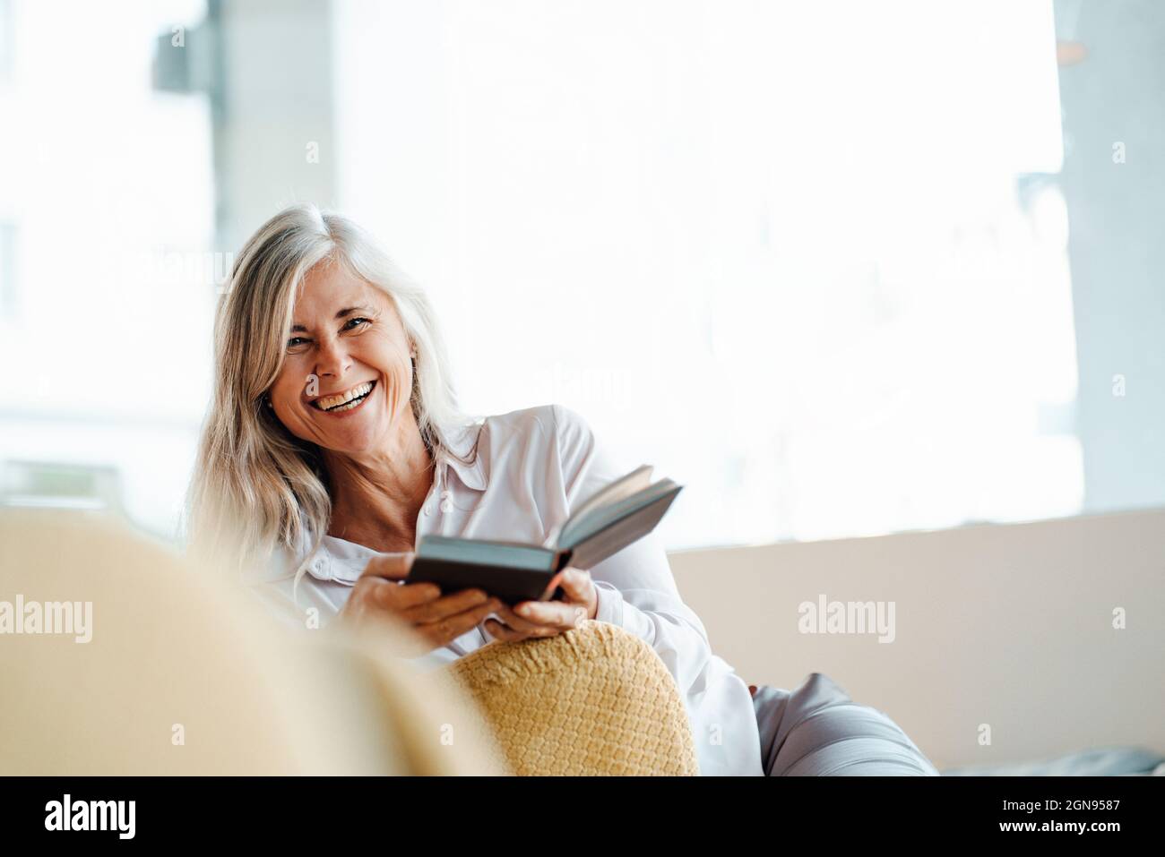 Femme mature lisant le livre tout en étant assise dans un café Banque D'Images