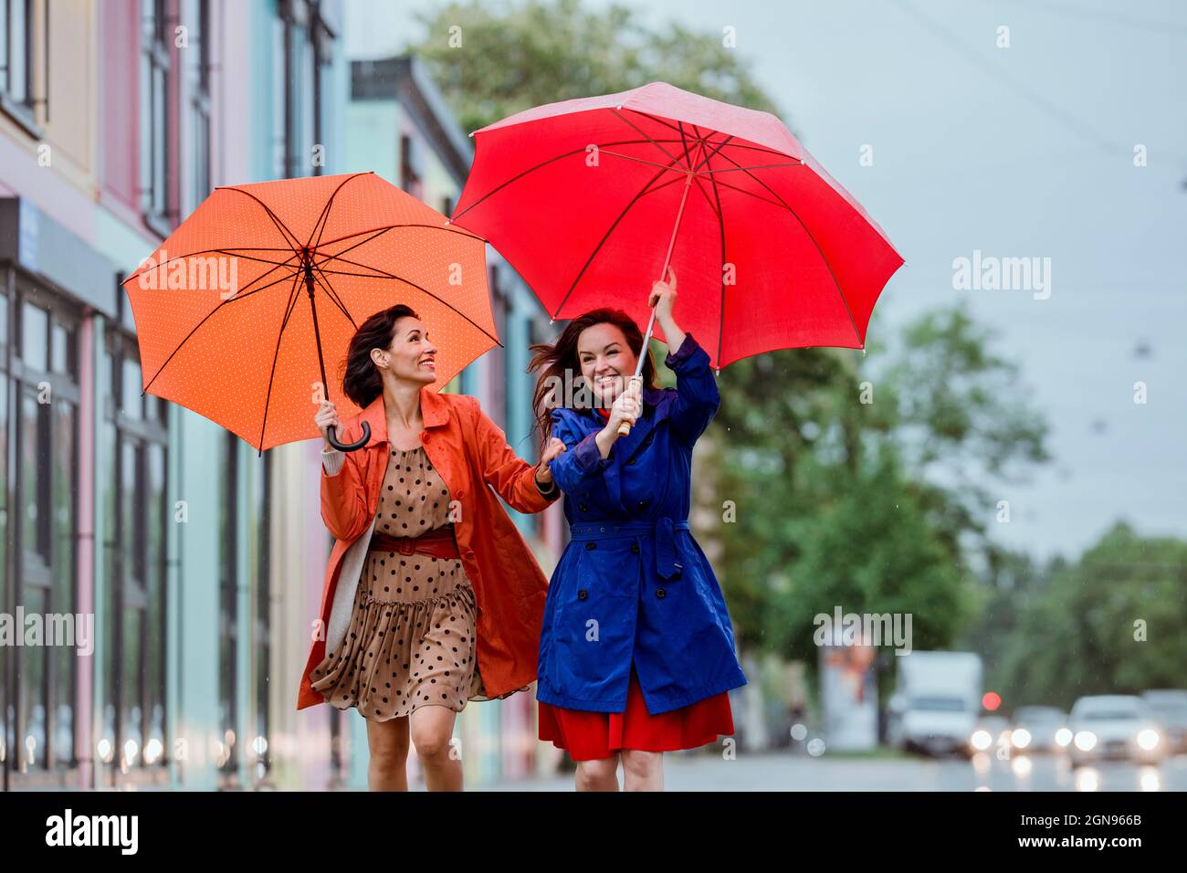 Des amies gaies se débattant avec un parapluie sous la pluie Banque D'Images