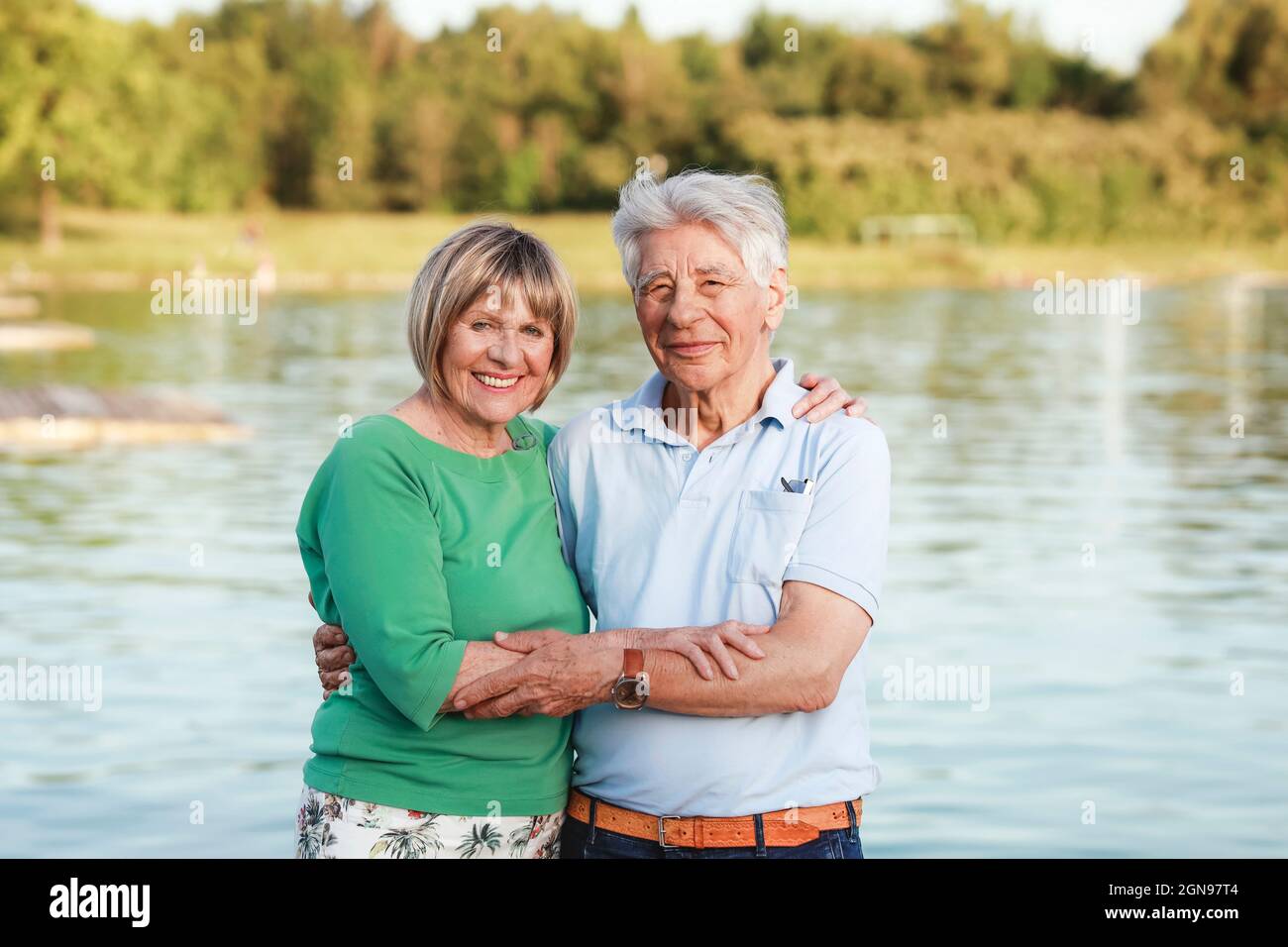 Couple senior souriant debout avec le bras autour du lac Banque D'Images