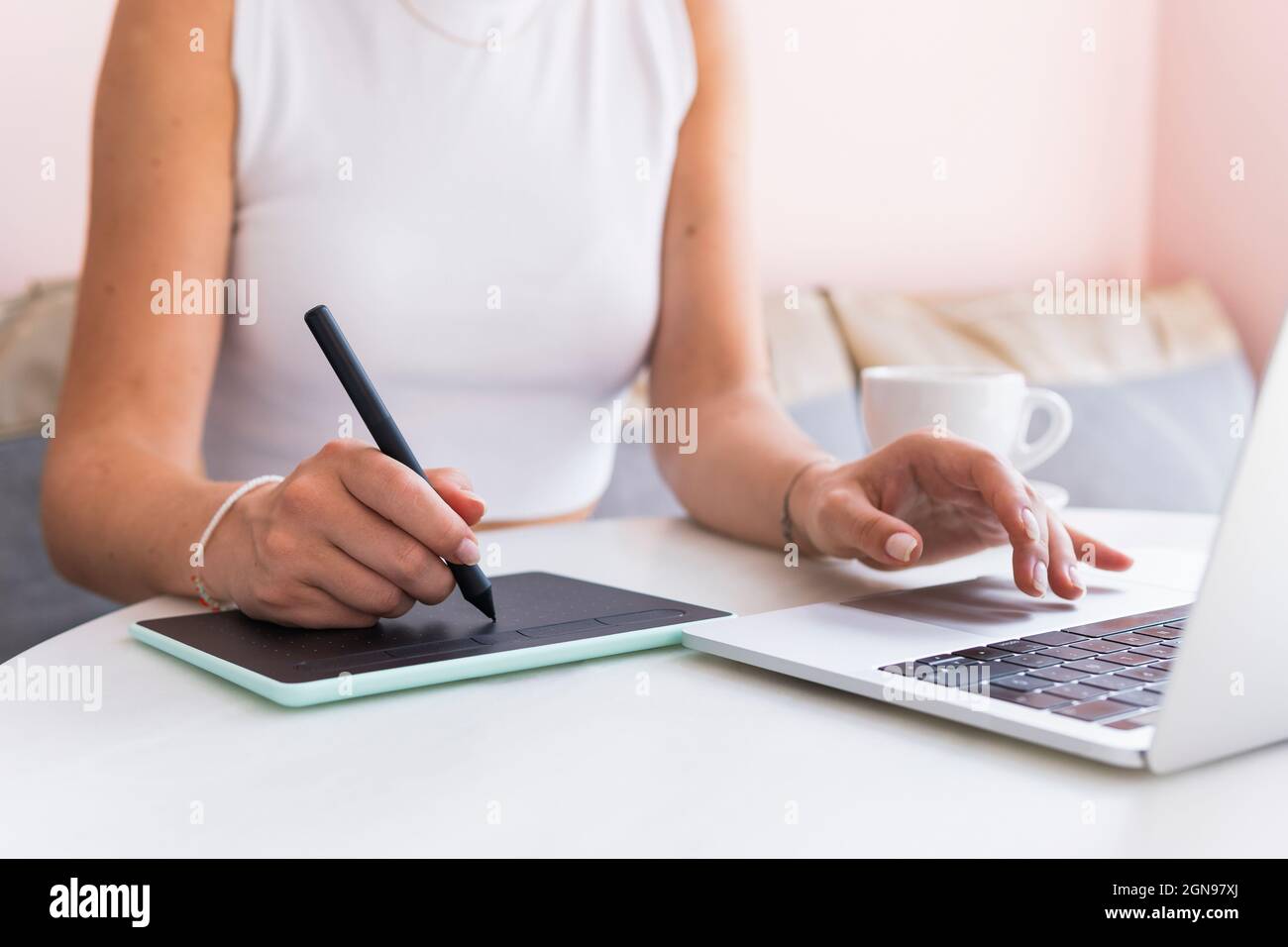 Femme design professionnel utilisant un ordinateur portable et une tablette graphique dans un café Banque D'Images