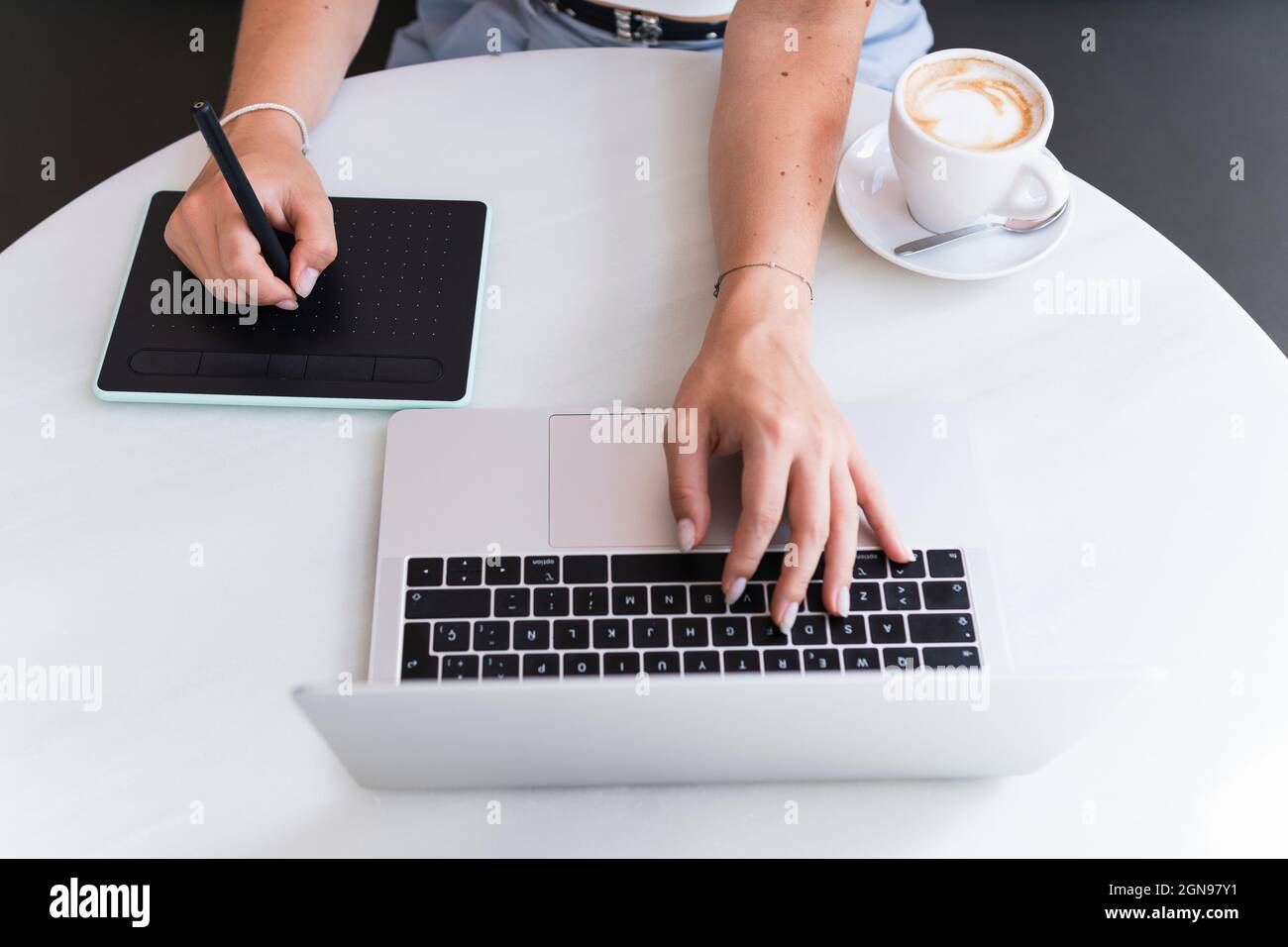 Femme design professionnel assis avec ordinateur portable et tablette graphique dans le café Banque D'Images