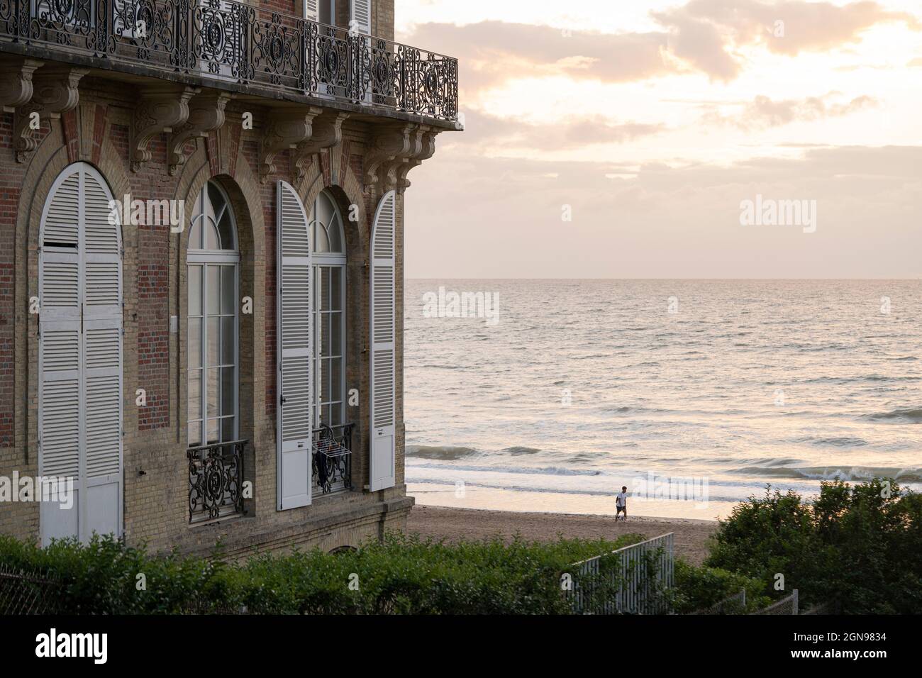 Luxueux balcon donnant sur la Manche au coucher du soleil, un homme court sur la plage Banque D'Images