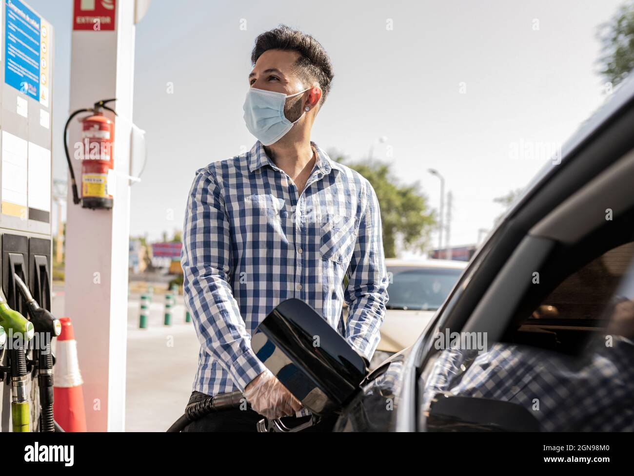 Homme avec masque facial de protection ravitailleur en gaz en voiture Banque D'Images