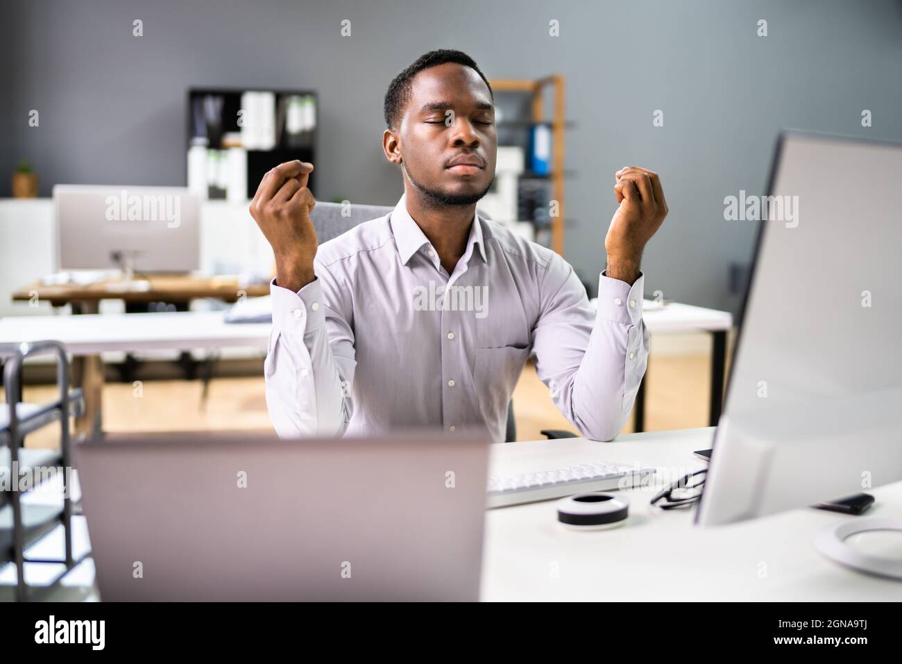 Méditation d'homme afro-américain derrière l'ordinateur au bureau Banque D'Images