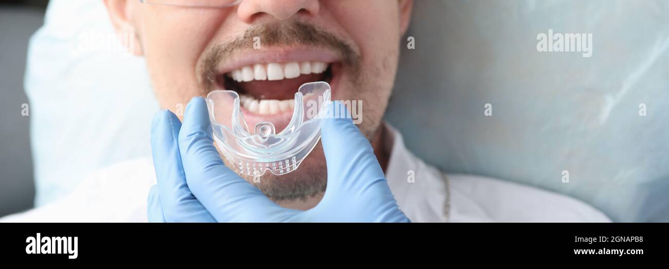 Dentiste essayant sur le protecteur buccal pour homme patient Banque D'Images
