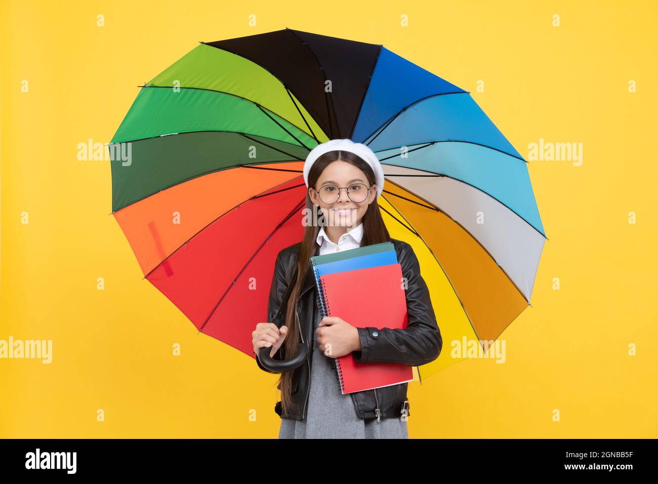enfant adolescent sous parasol coloré. enfant en béret avec parapluie arc-en-ciel. saison d'automne. Banque D'Images