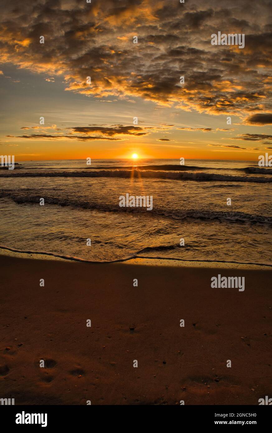 Le lever du soleil d'une belle plage par une journée nuageux Banque D'Images