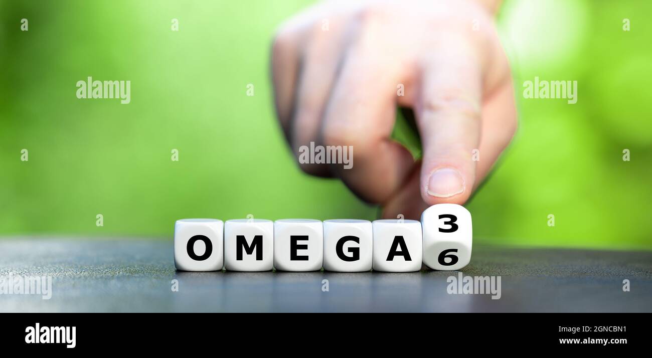 Symbole pour une alimentation saine. La main tourne les dés et change l'expression 'Omega 6' en 'Omega 3'. Banque D'Images