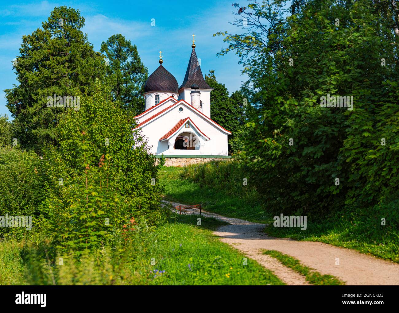 Église russe blanche en été avec ciel nuageux en arrière-plan et route en premier plan Banque D'Images