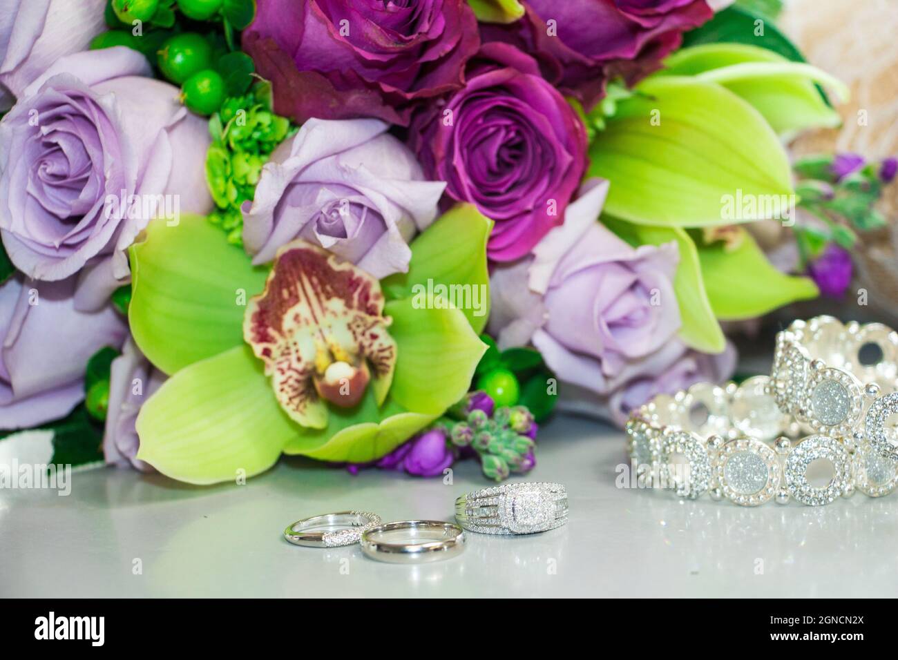 Gros plan de trois bagues avec deux bracelets et un beau bouquet de fleurs Banque D'Images