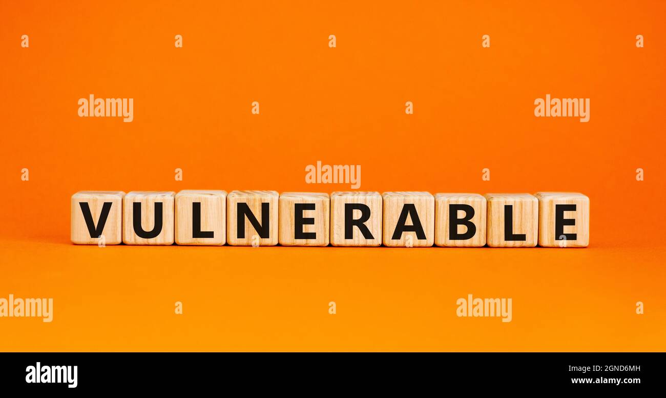 Symbole vulnérable. Le mot vulnérable sur les cubes en bois. Belle table orange, fond orange. Concept d'entreprise et de vulnérabilité. Copier l'espace. Banque D'Images