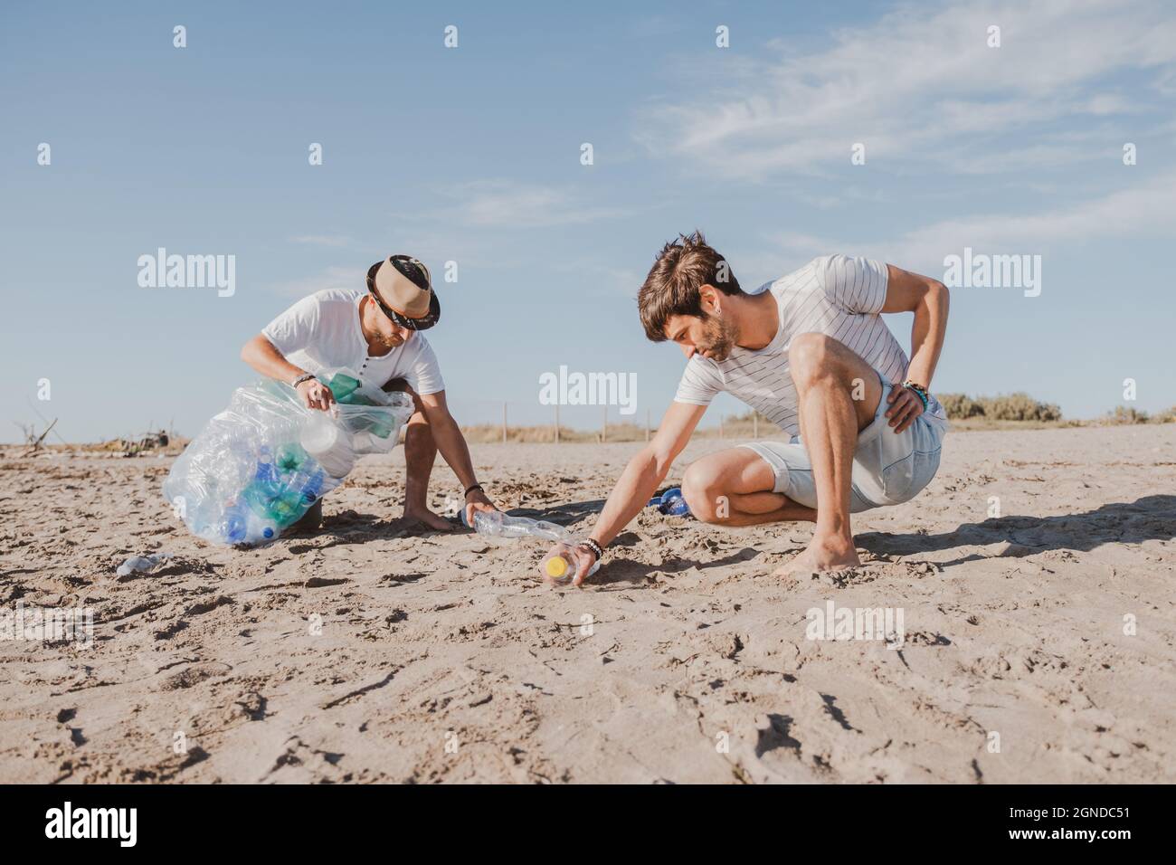Groupe d'amis activistes collectant des déchets plastiques sur la plage. Les gens nettoyant la plage, avec des sacs. Concept de conservation de l'environnement et de l'océan Banque D'Images
