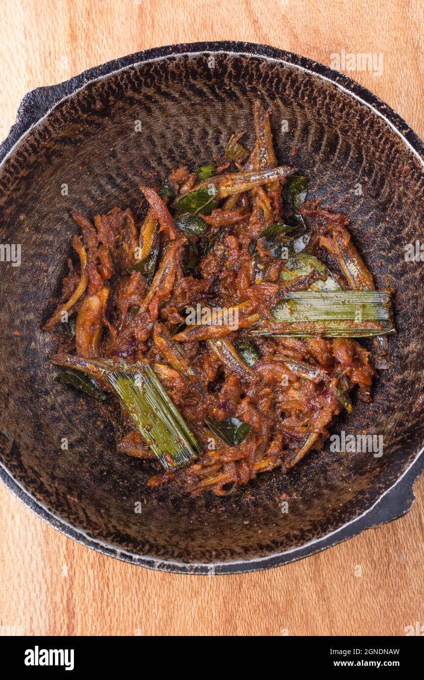 dans une casserole, mélanger le petit plat de poisson sec frit, les fruits de mer cuits avec de l'huile de coco et des épices, en gros plan Banque D'Images