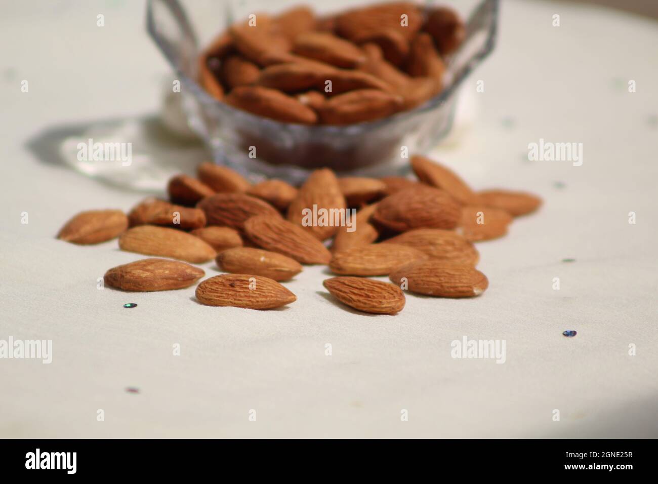 Amandes fraîches dans le bol en verre sur fond blanc amandes riches en vitamines faible profondeur de champ Banque D'Images
