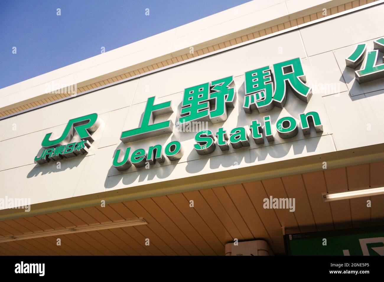 Façade extérieure du bâtiment de la gare d'Ueno avec un grand panneau vert. Personne. Fond ciel bleu clair. Banque D'Images