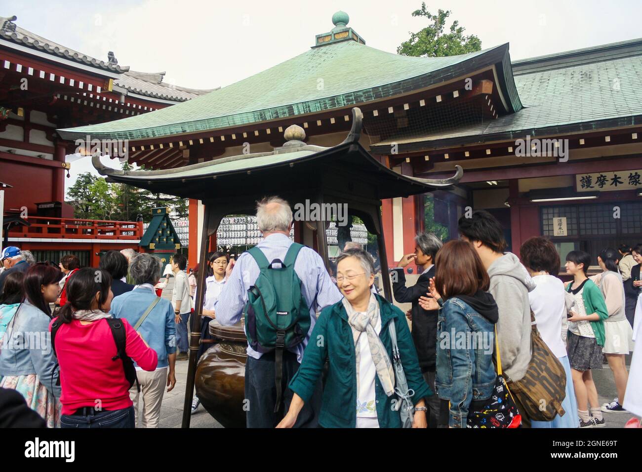 Une foule de personnes se rassemblent autour d'un brûleur d'encens au temple Sensoji couvrant ou baignant de fumée avant de prier dans la salle de prière. Banque D'Images