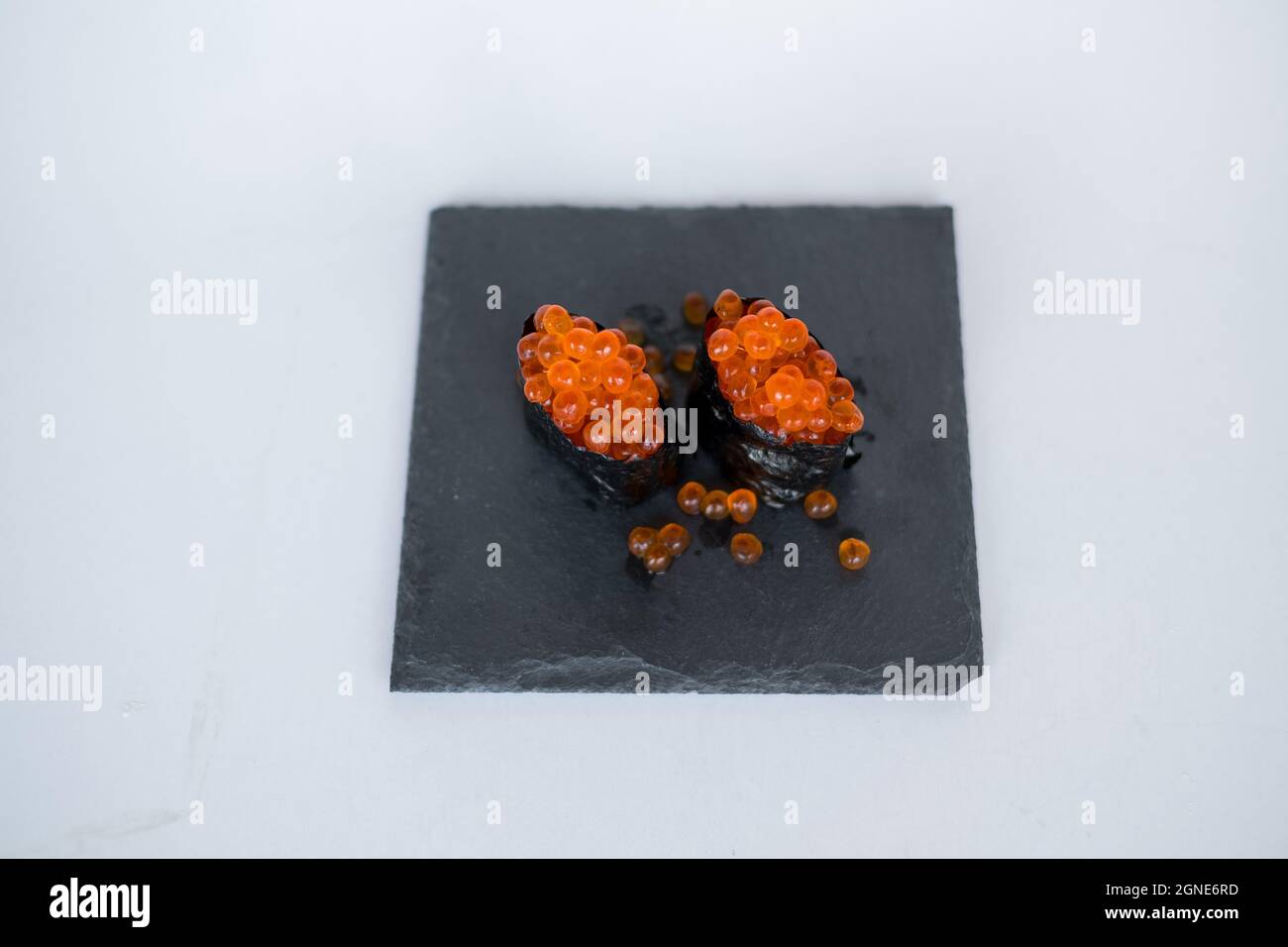 Gunkan Maki avec caviar de saumon servi sur plateau noir isolé sur fond blanc. Cuisine traditionnelle japonaise. Photo de haute qualité Banque D'Images