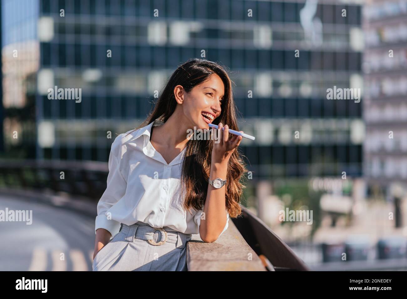 portrait horizontal d'une femme indienne attrayante envoyant un message vocal avec son smartphone. Elle est dans le quartier financier Banque D'Images