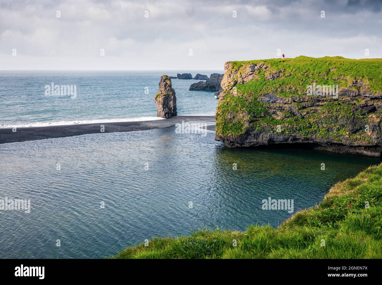 Pittoresque lever de soleil d'été dans la réserve naturelle de Dyrholaey avec homme solitaire sur le rocher. Grande vue sur l'arche de Dyrholaey, côte sud de l'Islande, Europe. INST Banque D'Images