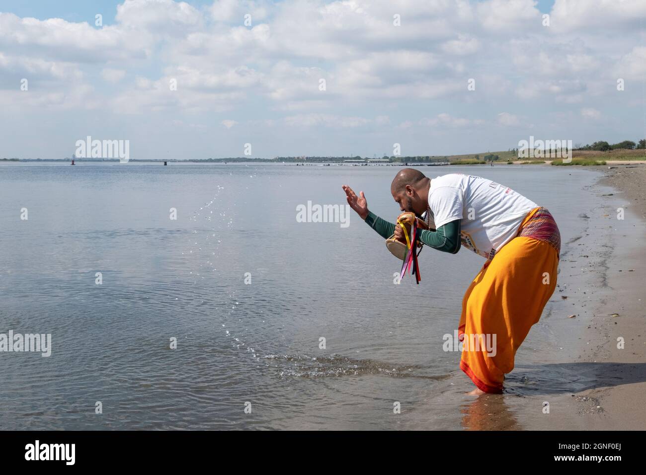 Un adorateur hindou dévorant des raies et des éclaboussures d'eau au bord de la baie de Jamaica. À un service de Ganga et Kateri Amma Poosai. À Queens, New York. Banque D'Images