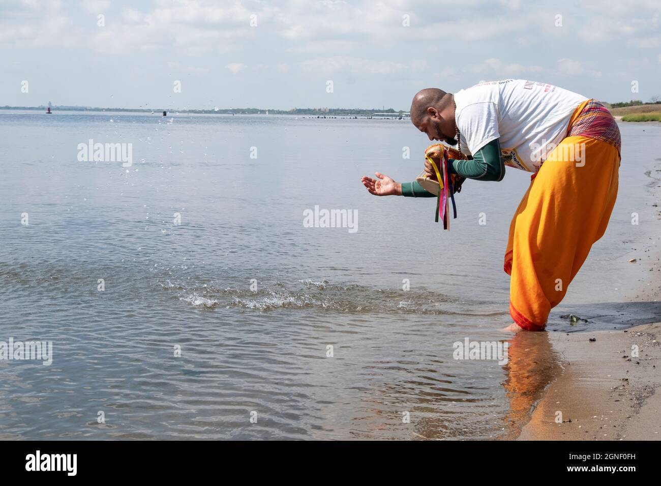 Un adorateur hindou dévorant des raies et des éclaboussures d'eau au bord de la baie de Jamaica. À un service de Ganga et Kateri Amma Poosai. À Queens, New York. Banque D'Images