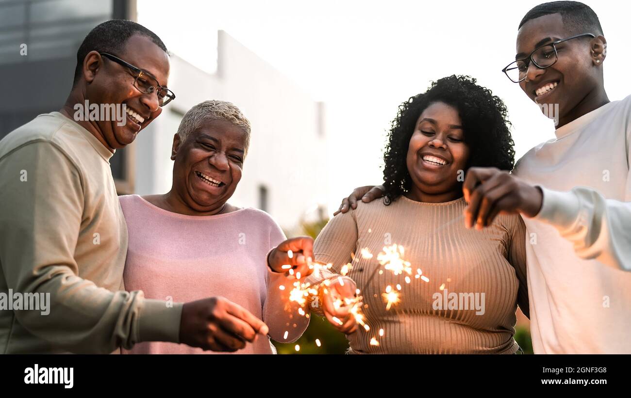 Bonne famille africaine célébrant des vacances avec des feux d'artifice de sparklers à la fête maison Banque D'Images